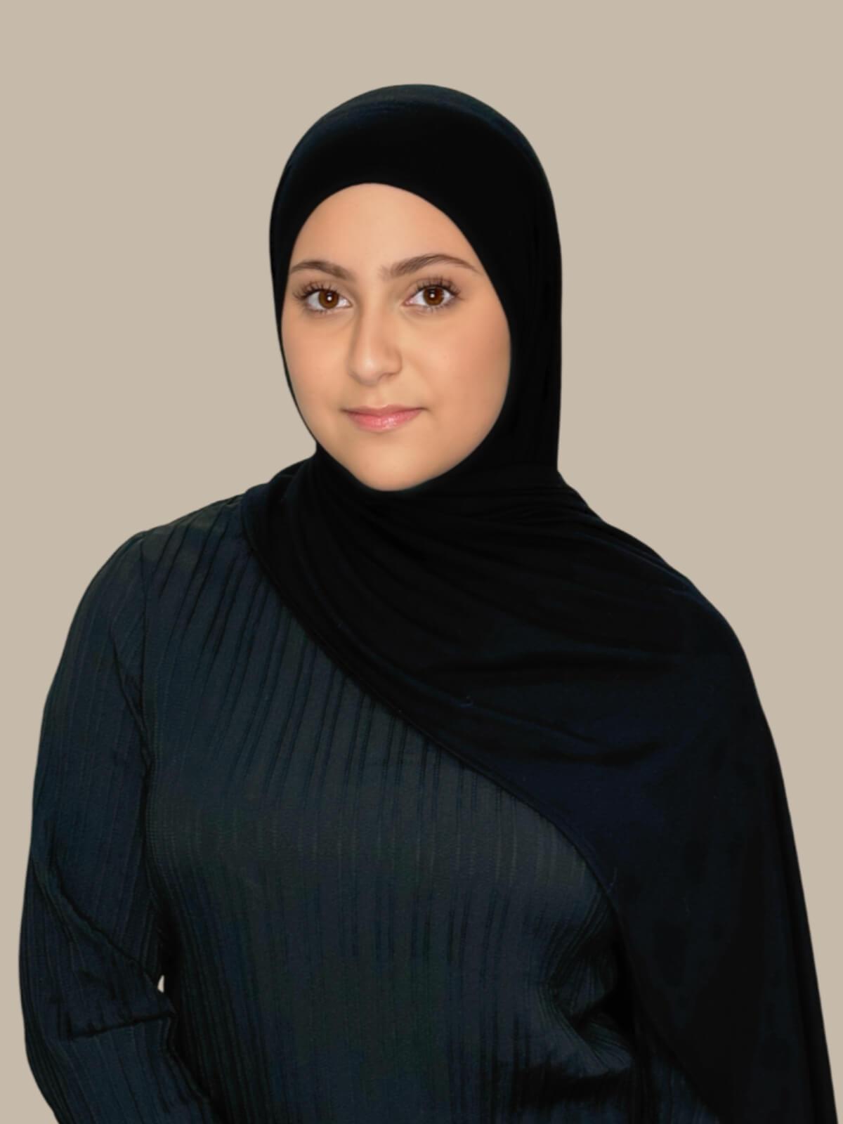 Black Pre-Sewn Jersey Hijab in Modish Girl size, front view on model with hijab draped over shoulder showing fabric length and fit.