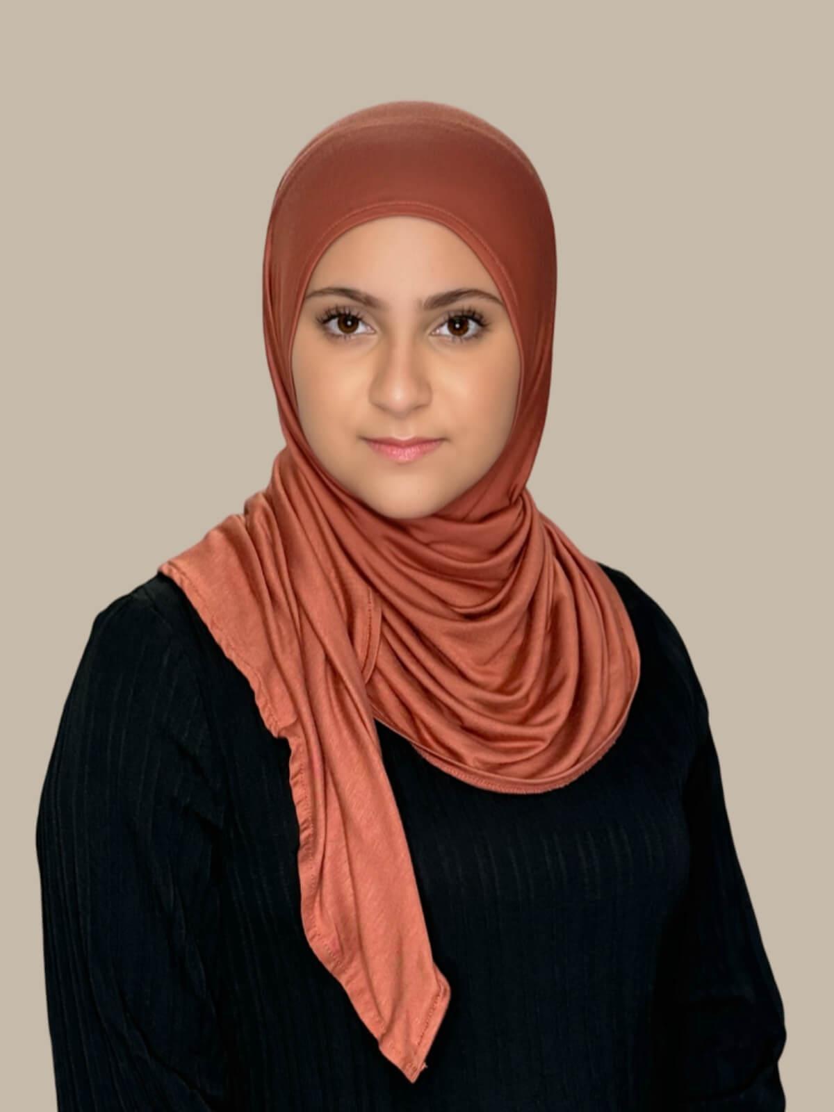 Brick Red Pre-Sewn Jersey Hijab in Modish Girl size, front view on model with hijab wrapped neatly around shoulders showing smooth fit and soft stretch fabric.
